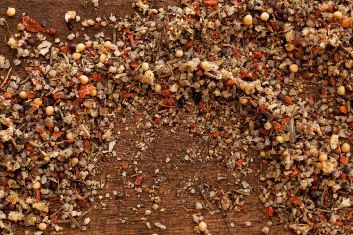 Coarse seasoning blend with herbs and seeds scattered on a wood board