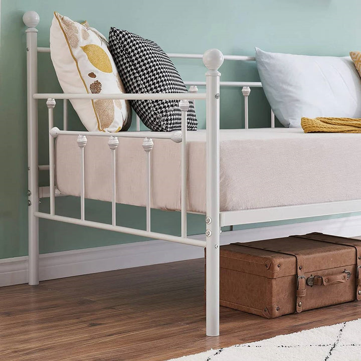 White metal twin daybed frame, side view with paneled guardrails and finials