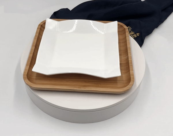 Square white porcelain plate stacked on bamboo serving board