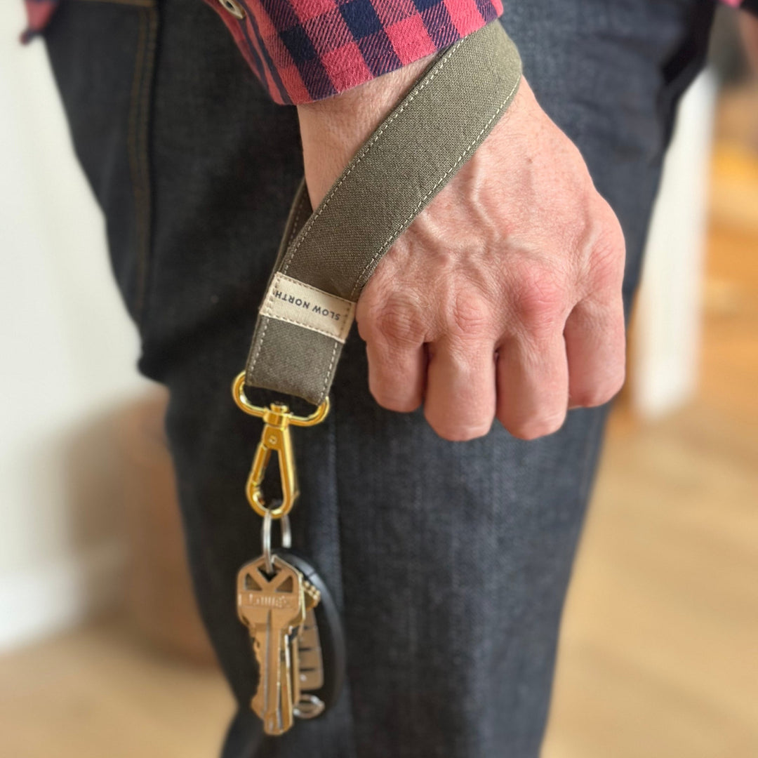 Olive wrist strap keychain worn on wrist with gold keyrings and clip