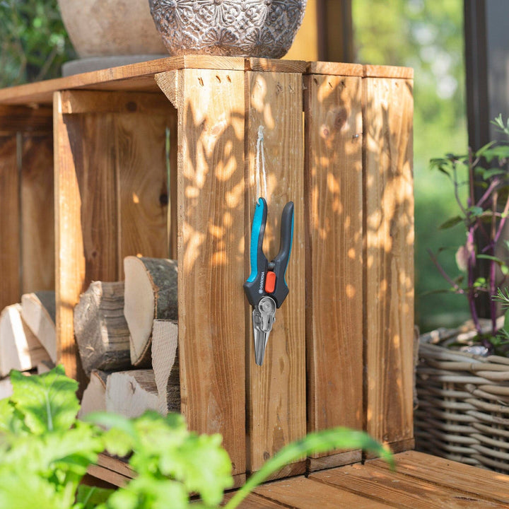 GripCut scissors hanging on a wooden fence post with blue and black handles