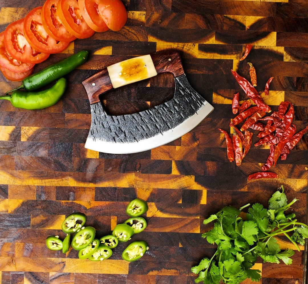 Hand-forged ULU knife with dark hammered crescent blade and wood handle with amber inlay
