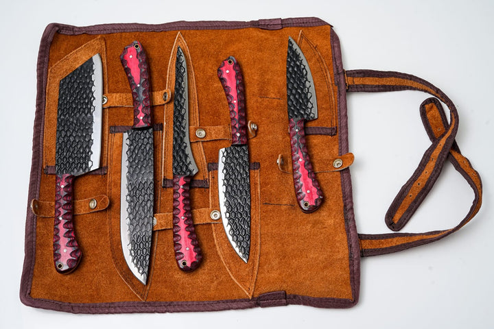 Open leather knife roll holding five dark carbon-steel knives with red diamond handles