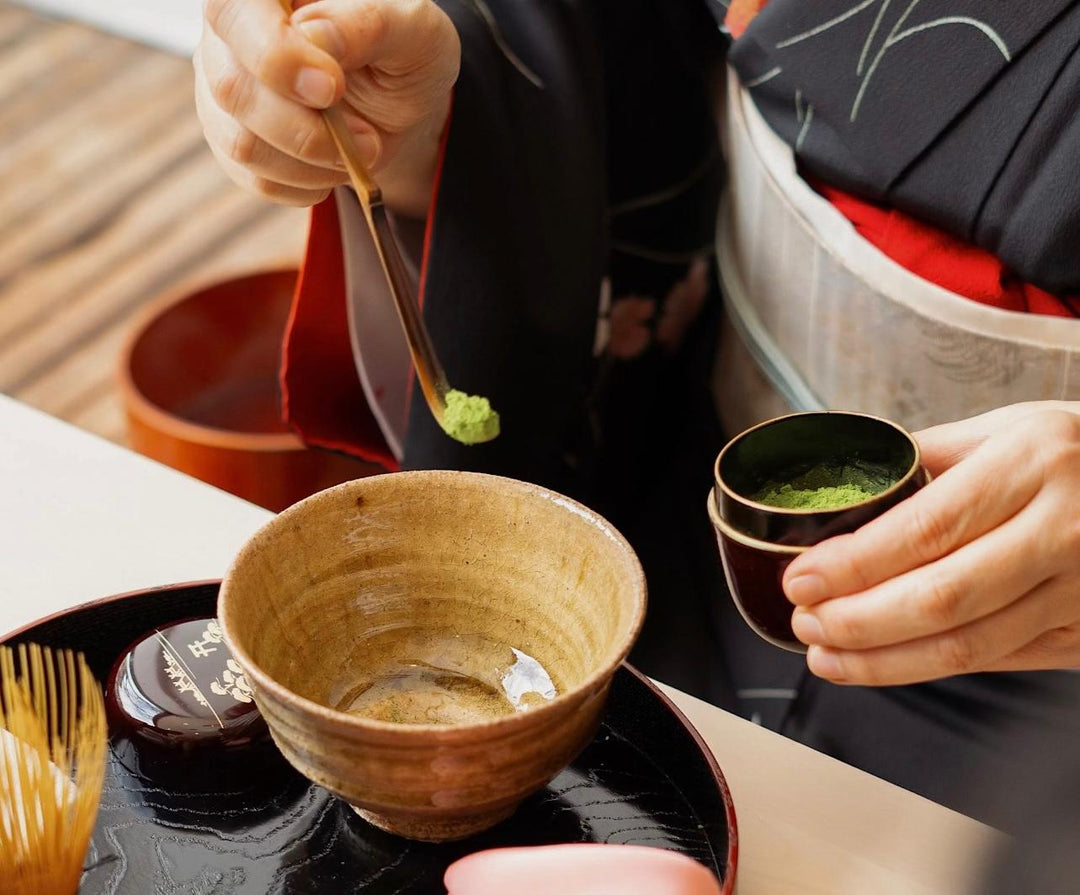 Single-cultivar matcha being whisked in a bowl with a small cup of green powder