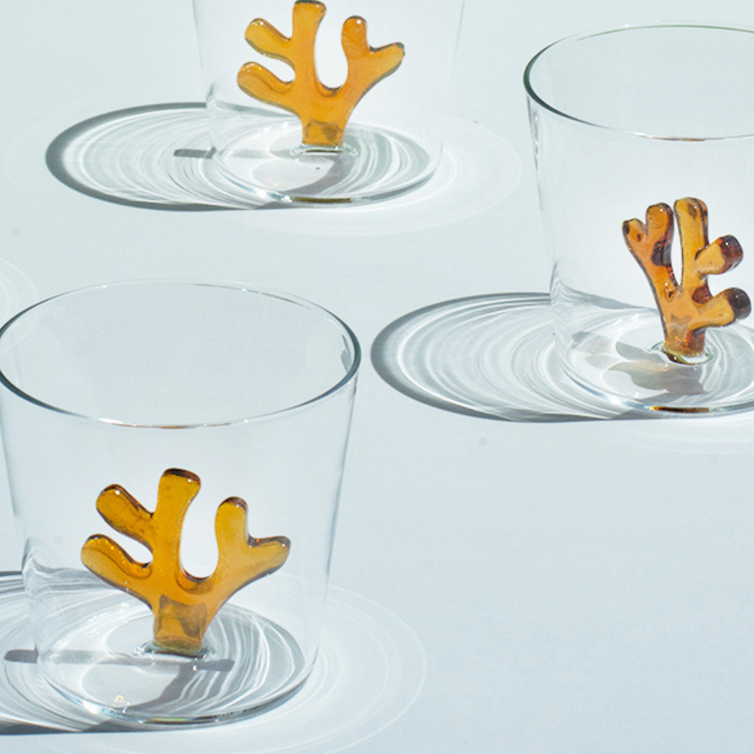 Clear glass water tumbler with orange coral insert, side view