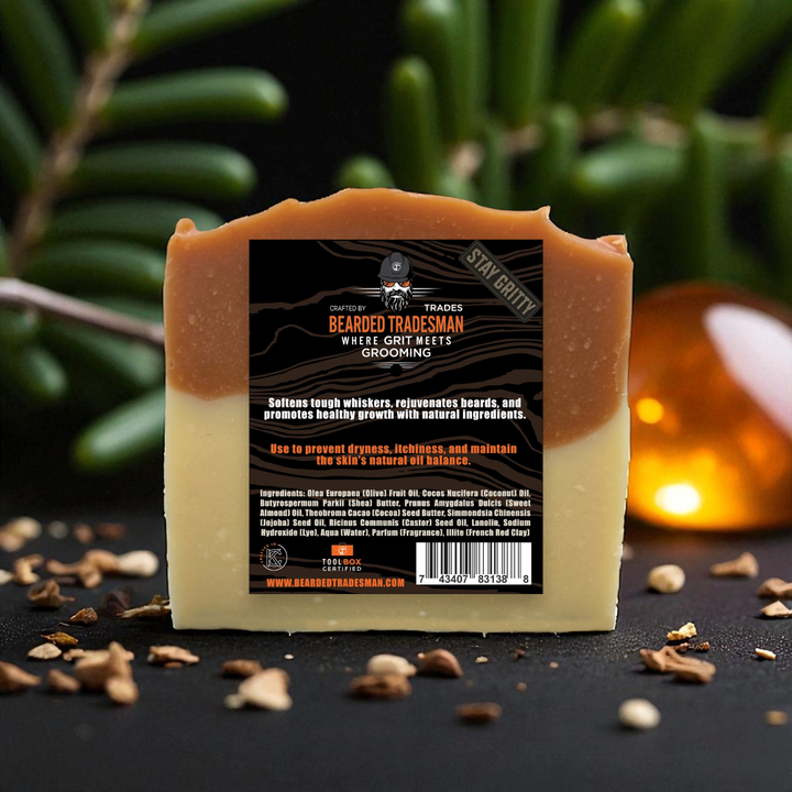 Whisker wash bar soap showing back label, set on stones with green leaves behind.