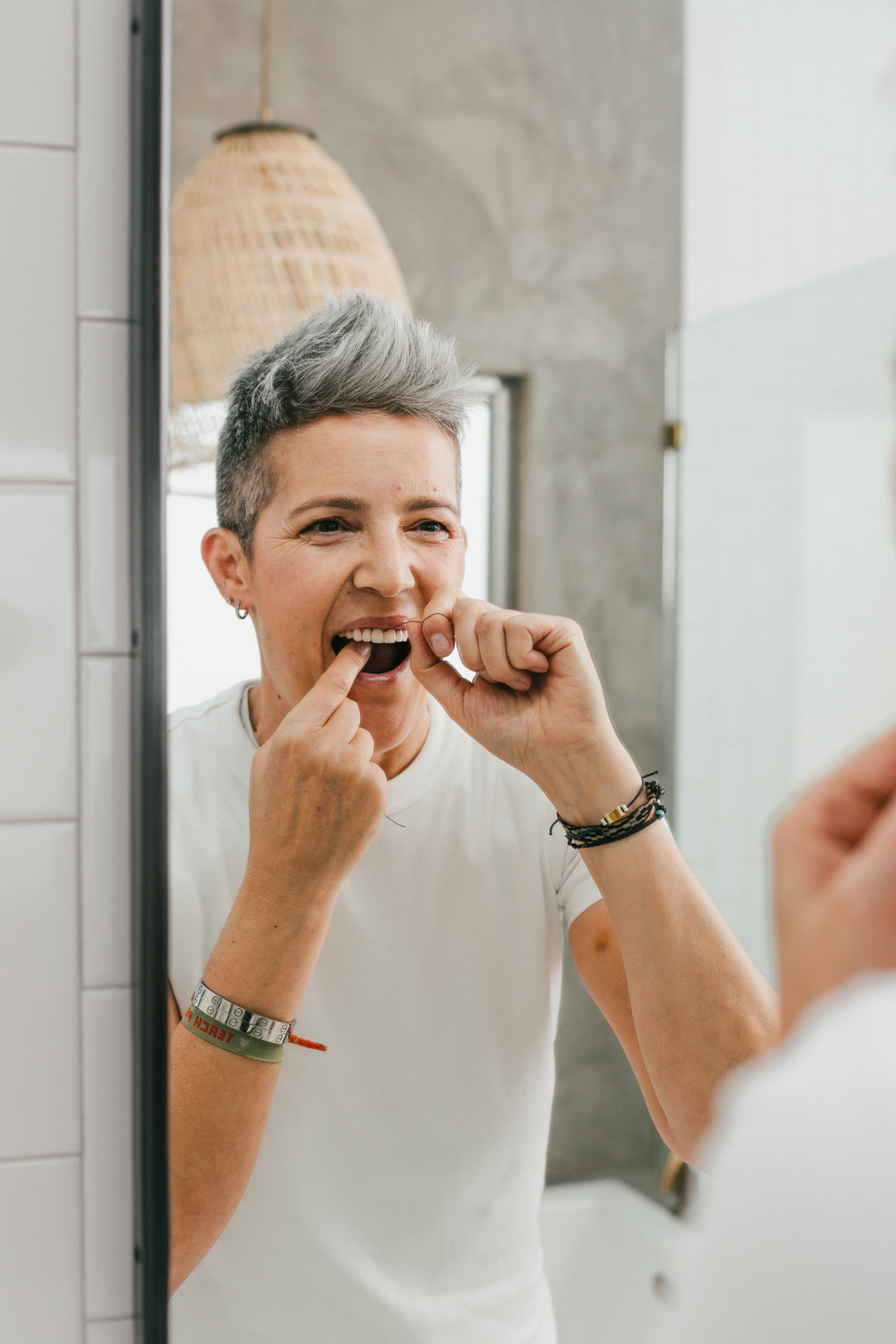 Woman flossing with a floss thread between her teeth, charcoal dental floss