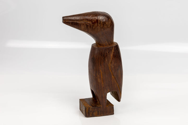 Dark brown wood bird figurine with side view and beak over flat base.