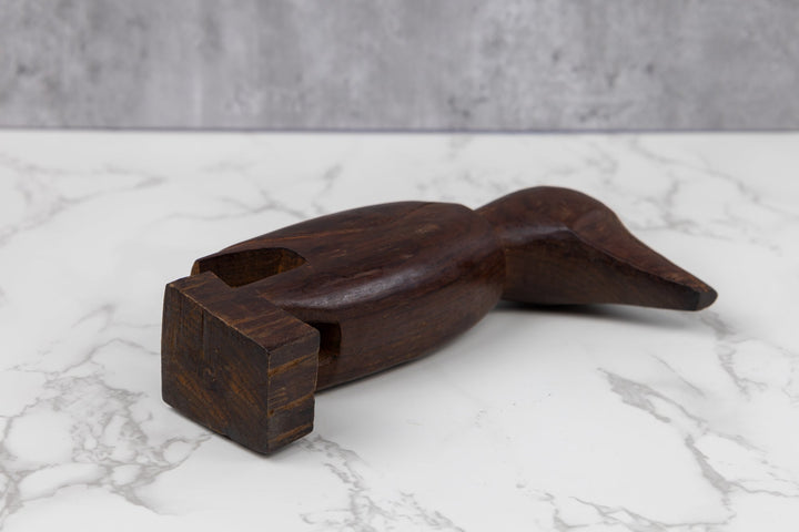 Dark brown wood bird figurine lying down with carved wings and body.