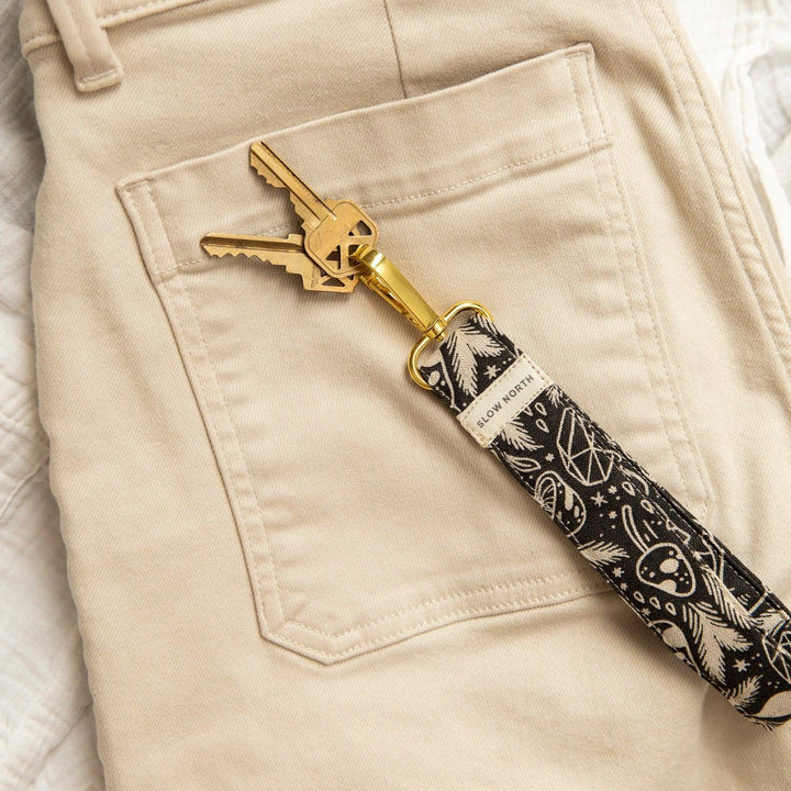 Detail of gold keys on black printed wristlet keychain with mushroom and star motifs