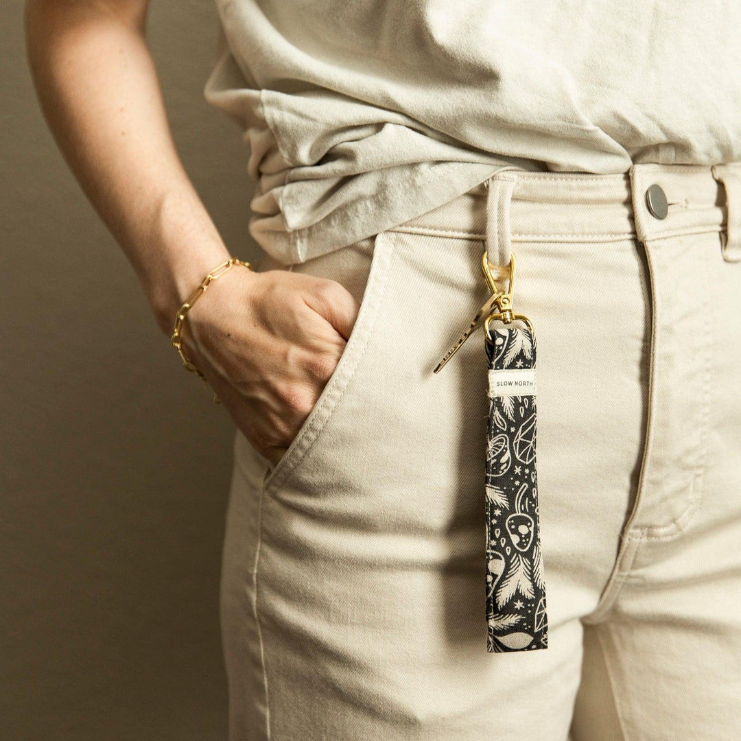 Wristlet keychain hanging from pocket: black fabric with white pattern and gold clasp