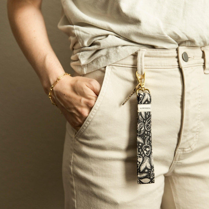 Wristlet keychain hanging from pocket: black fabric with white pattern and gold clasp