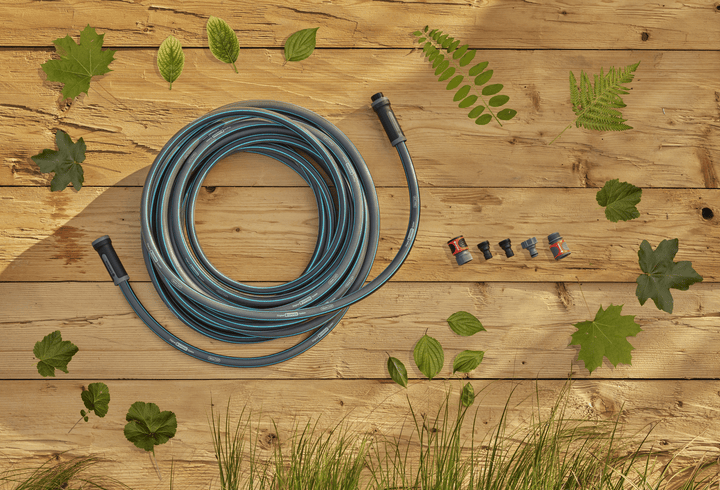 Garden hose coil with blue stripes and included hose fittings on a wooden surface
