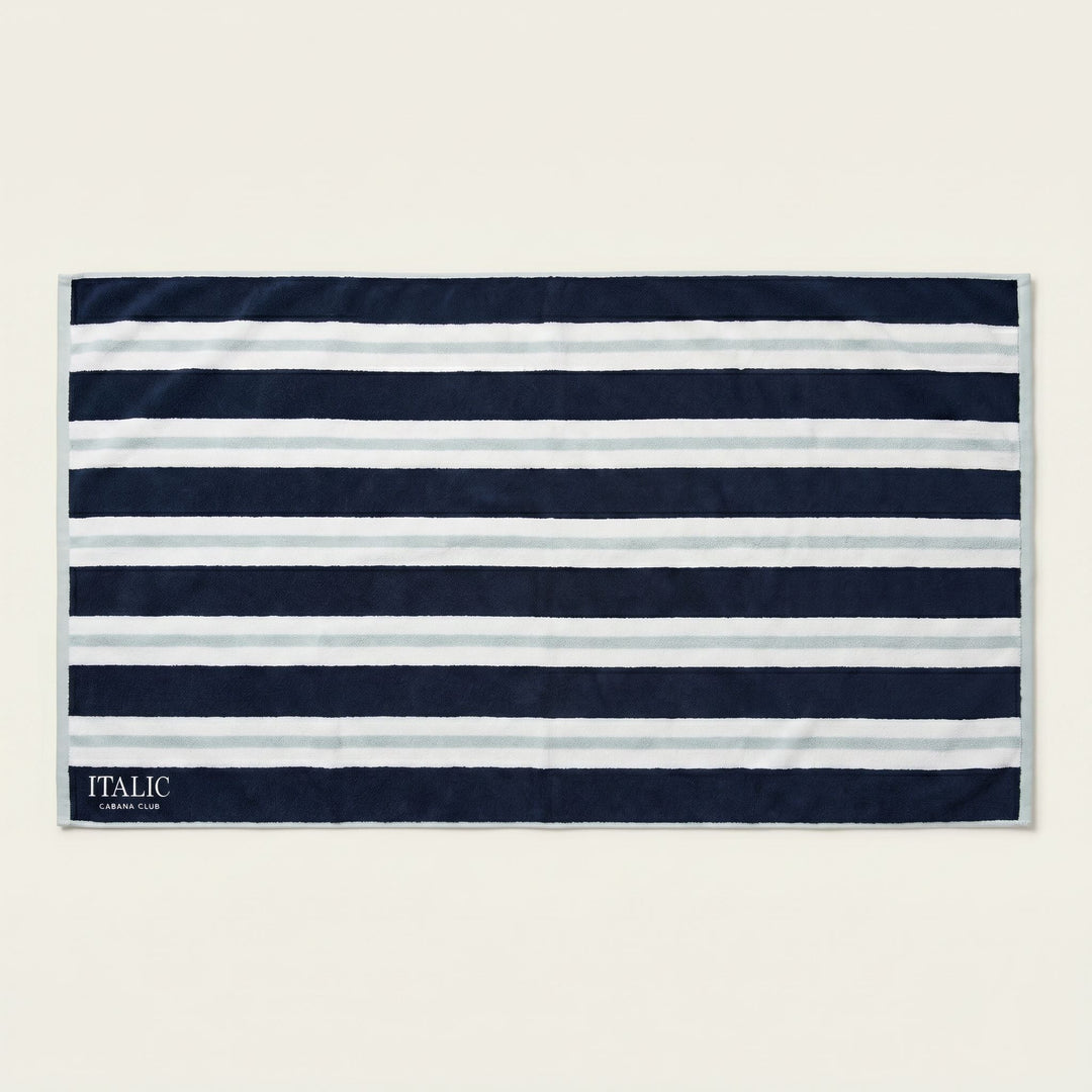 Cotton beach towel with navy and white horizontal stripes, ITALIC tag at corner