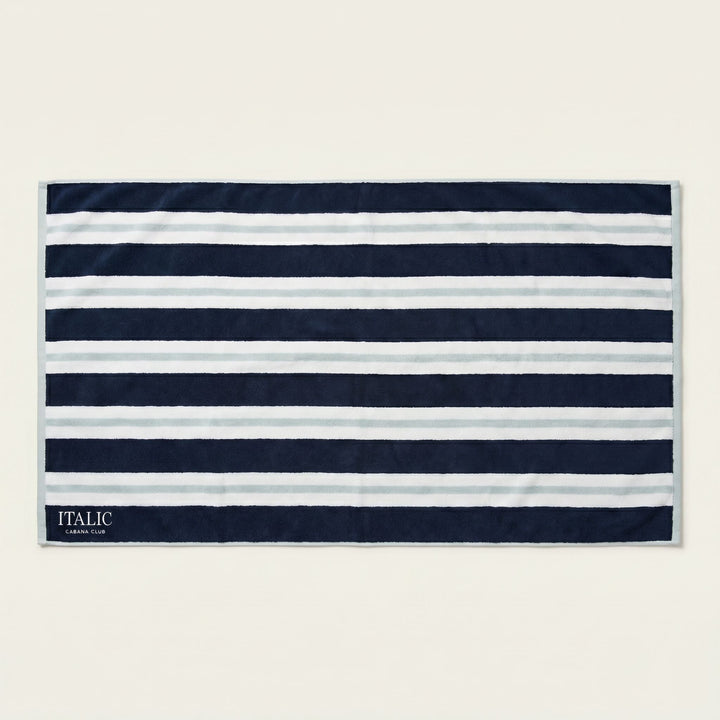 Cotton beach towel with navy and white horizontal stripes, ITALIC tag at corner