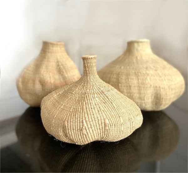 Close-up of woven tan basket with rounded belly and narrow neck, natural fiber texture