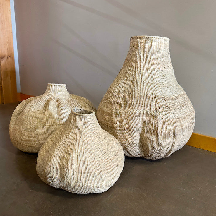 Three woven sculptural baskets with narrow necks and rounded bases, varying sizes.