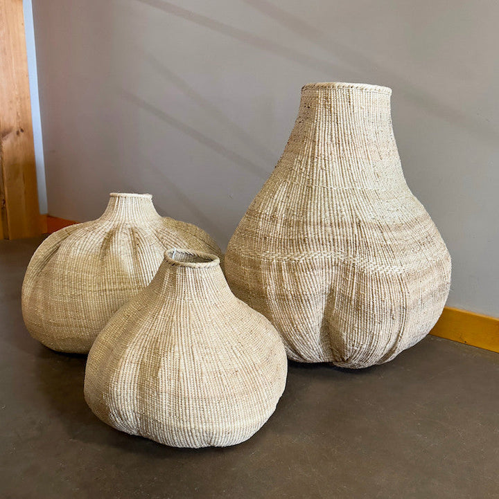 Three woven sculptural baskets with narrow necks and rounded bases, varying sizes.