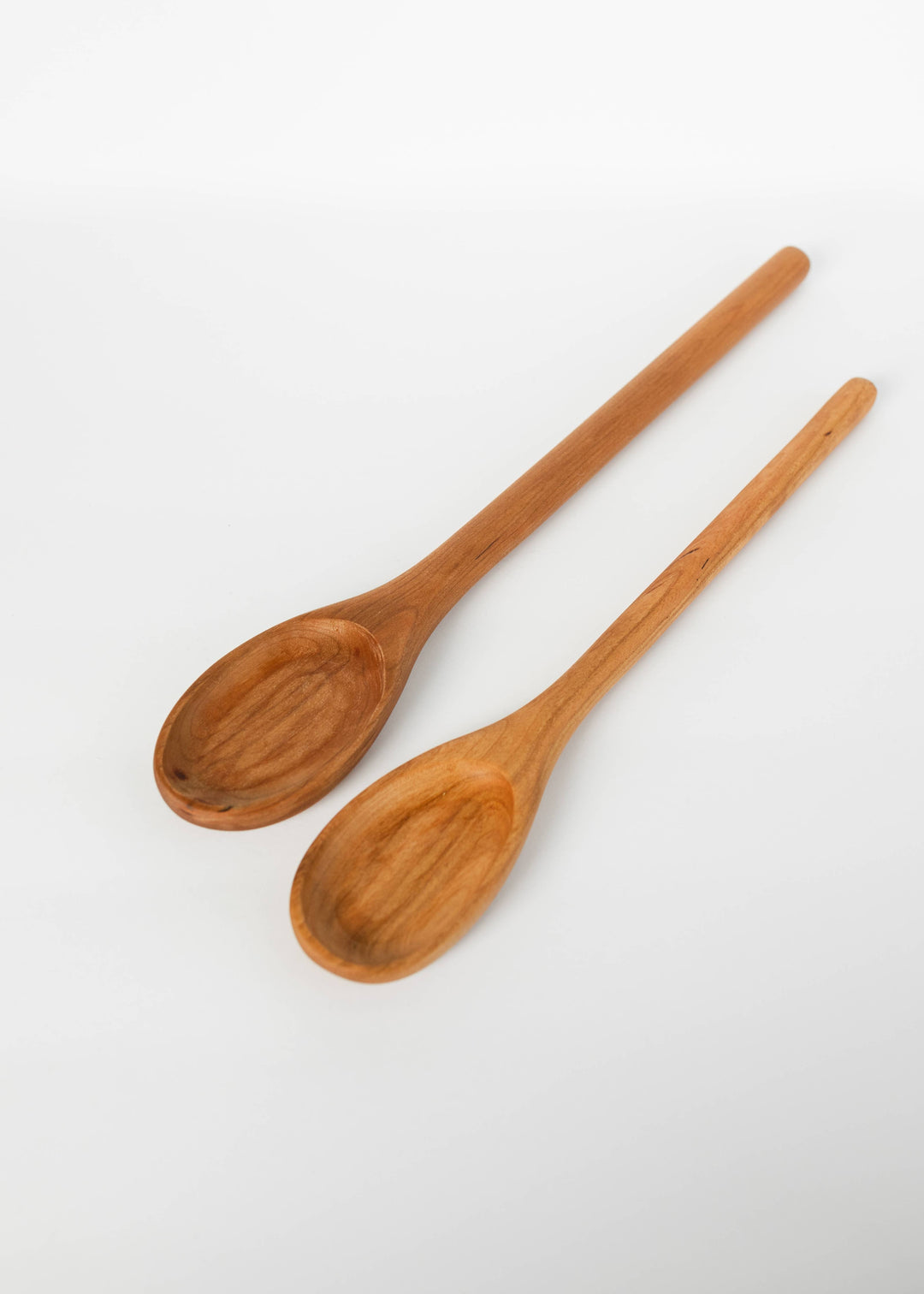 Pair of wooden spoons, oval bowls and long handles in medium warm-brown grain