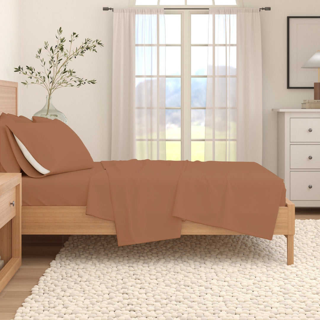 Solid cotton flannel sheet set in camel brown on a bed with folded flat sheet