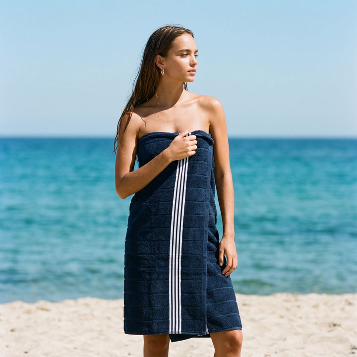 Navy Australian cotton towel wrap with white vertical stripes, worn outdoors by the sea