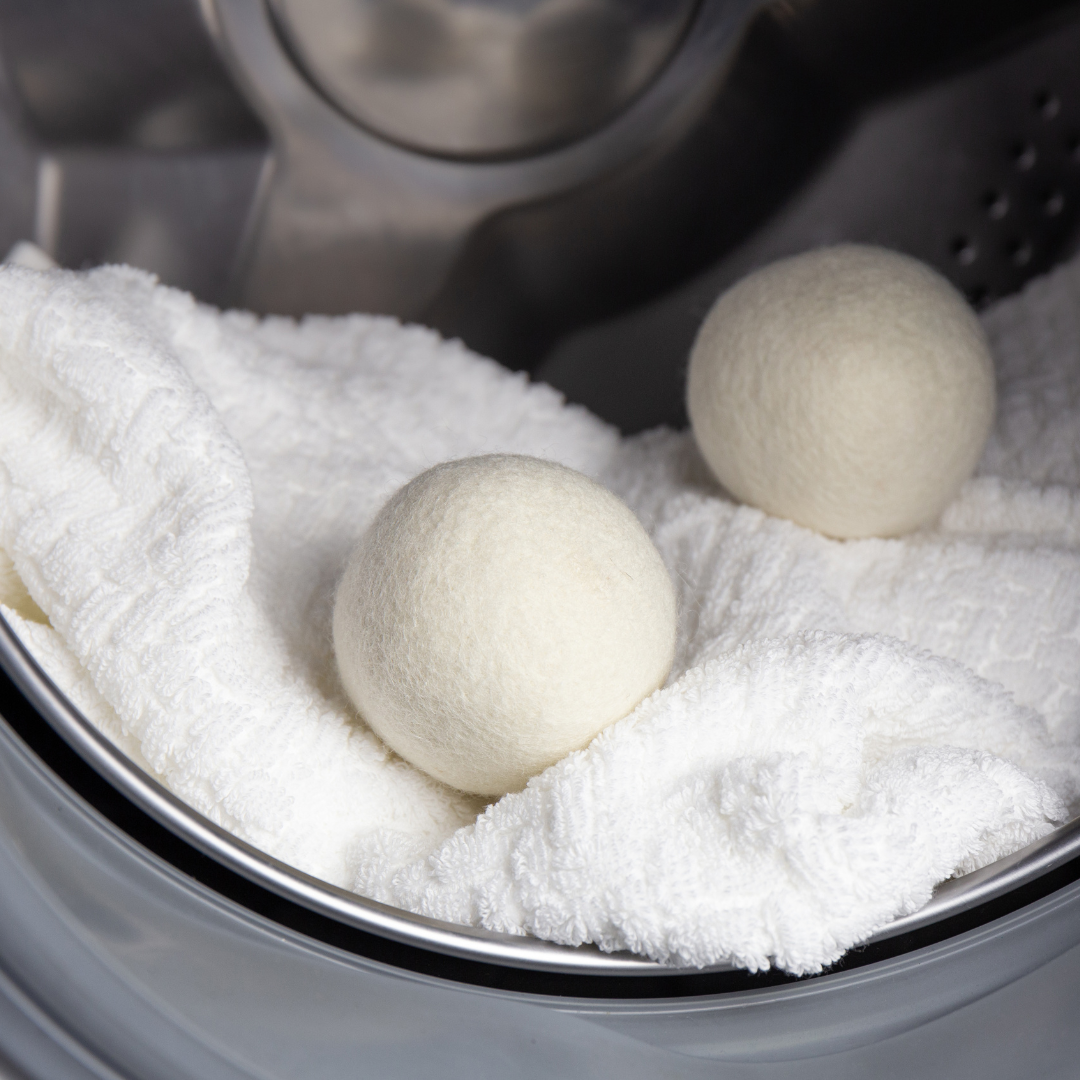 Felt alpaca wool dryer balls in a dryer with white towels and light-colored spheres