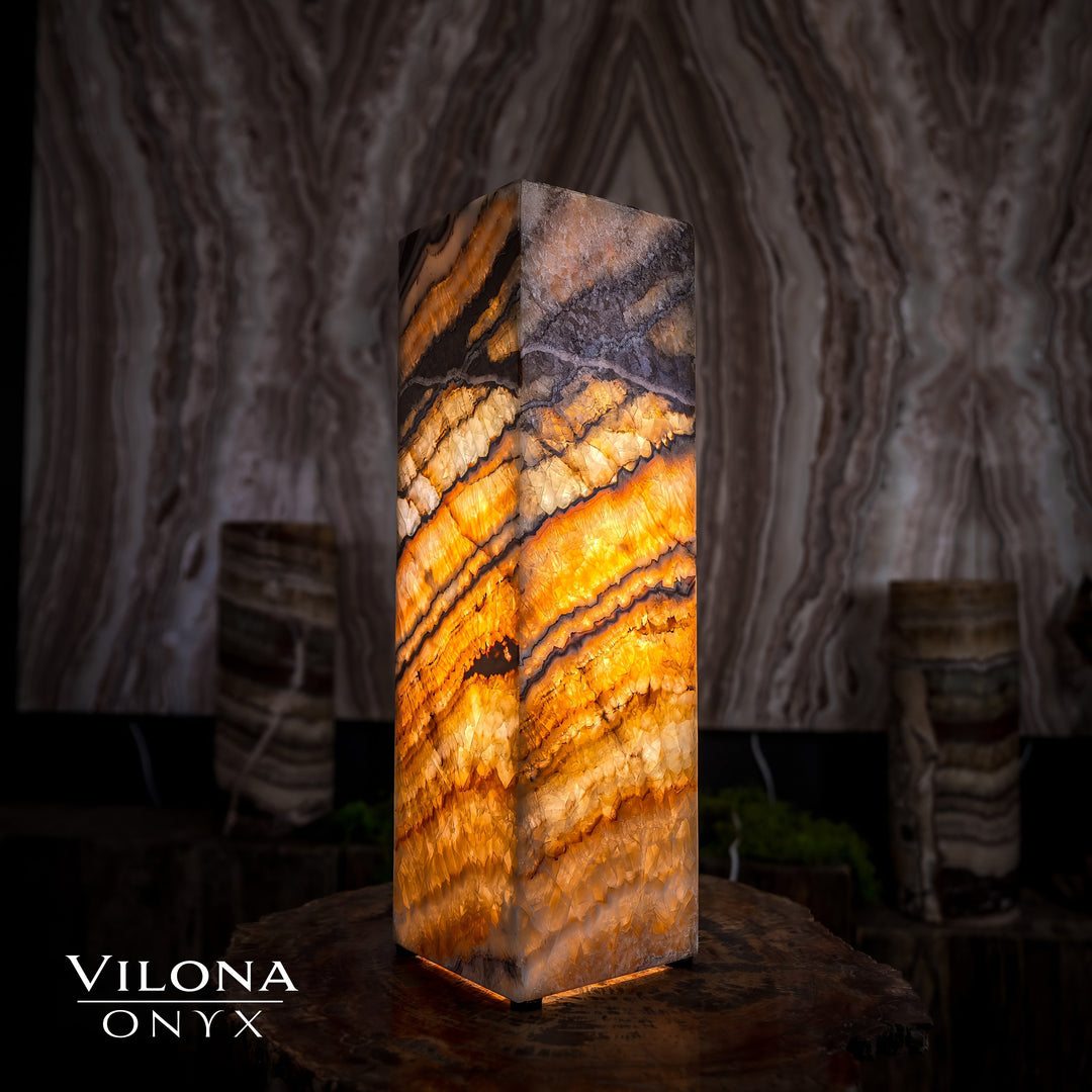 Small square table lamp with glowing amber onyx stripes and dark stone top