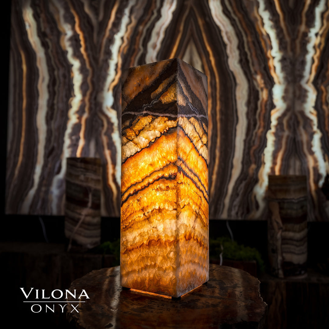Small square table lamp featuring glowing amber onyx stripes on a faceted prism body