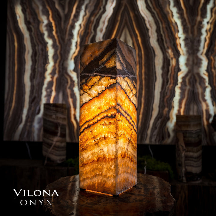 Small square table lamp featuring glowing amber onyx stripes on a faceted prism body