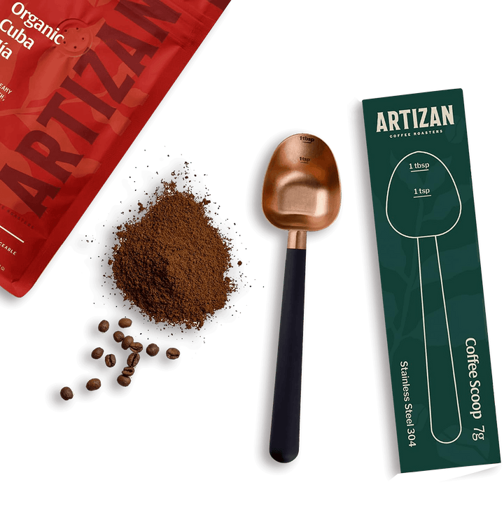 Rose gold coffee measuring scoop with coffee grounds and retail box