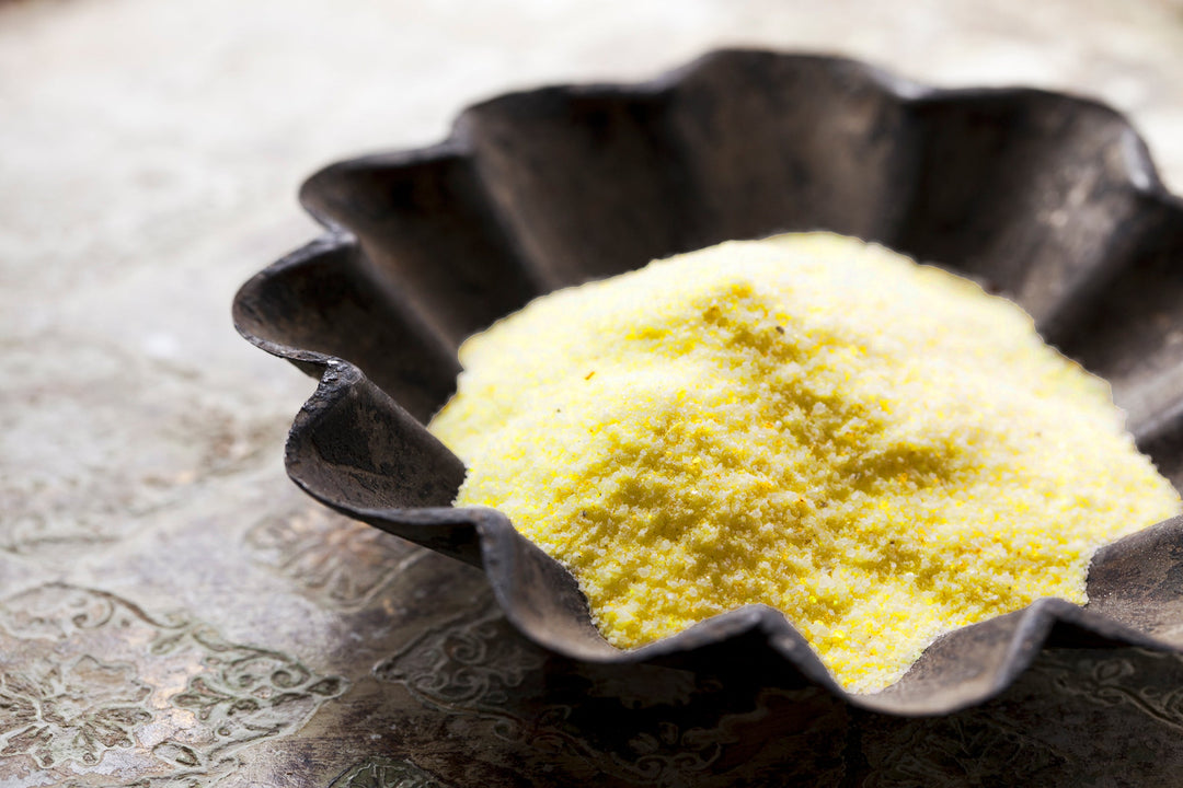 Asafoetida powder with yellow granules in a black dish