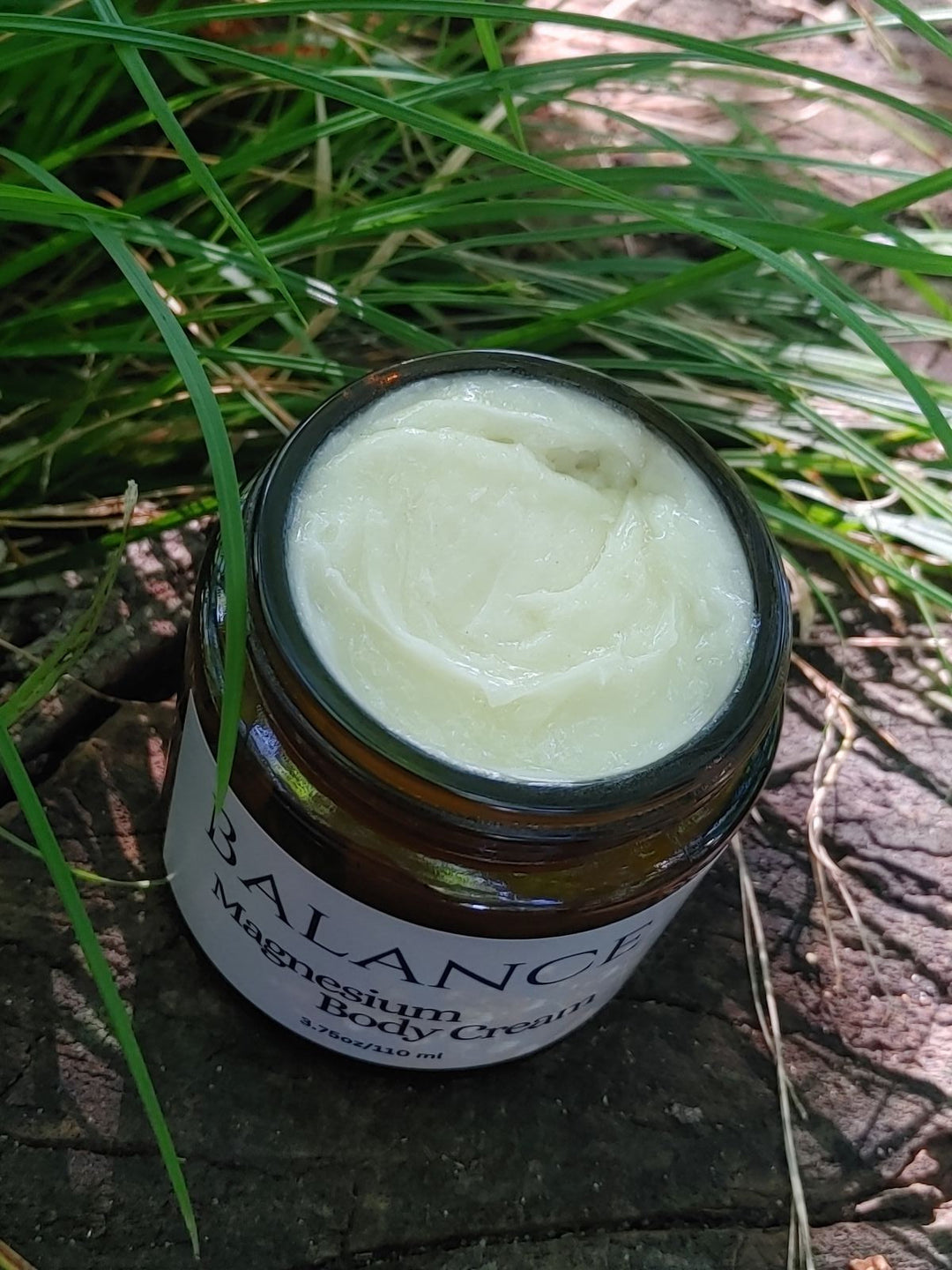 Magnesium body cream open jar with smooth pale cream inside, black lid
