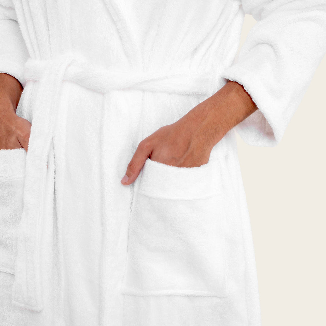 White plush bathrobe detail: tie belt at waist and front patch pocket opening.