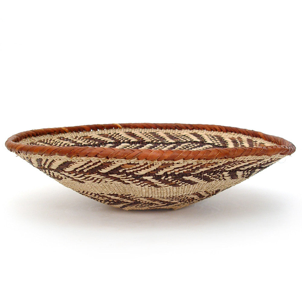 Small woven shallow oval basket with brown rim and geometric dark stripe weave
