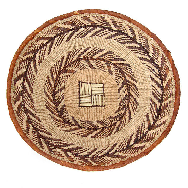 Small woven round basket, cream and dark brown spiral pattern with raised center emblem