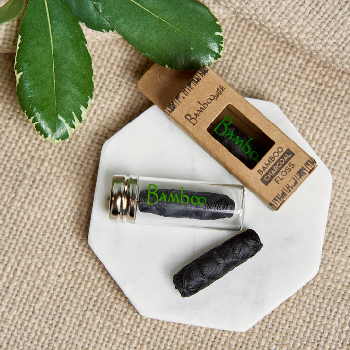 Charcoal bamboo floss yarn on a plate with glass vial and carton pack