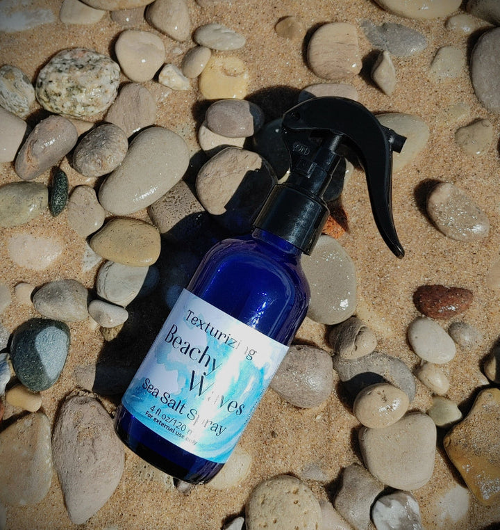 Sea salt spray bottle with black trigger sprayer on pebbles
