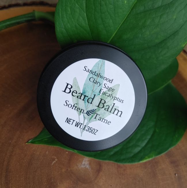 Beard balm tin with black lid and circular label, sandalwood and sage scent