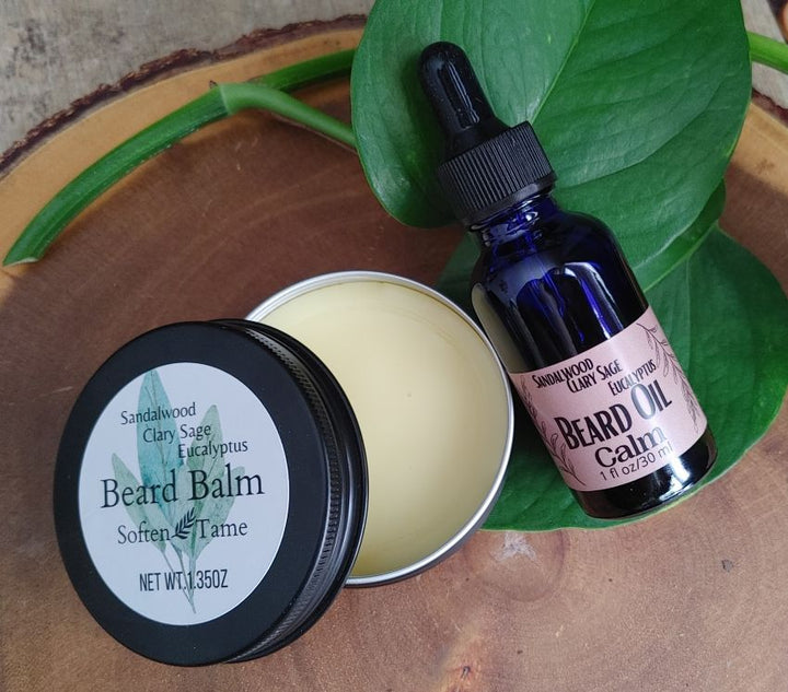 Beard balm tin with cream balm and black lid, plus dark blue dropper bottle