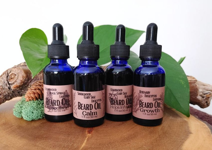 Set of four blue glass beard oil bottles with black droppers and pink labels
