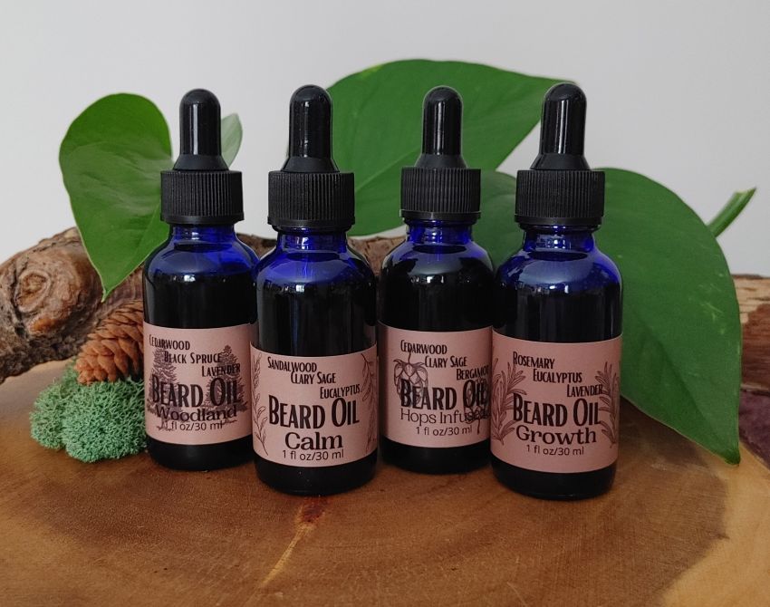 Set of four hydrating beard oil bottles with black dropper caps and labeled benefits