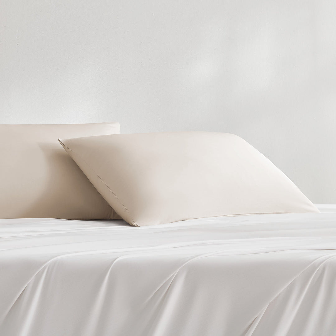 Cream-beige cooling pillowcase on bed, smooth finish with folded edge