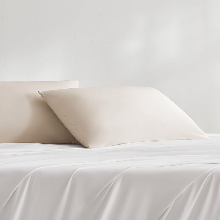 Cream-beige cooling pillowcase on bed, smooth finish with folded edge