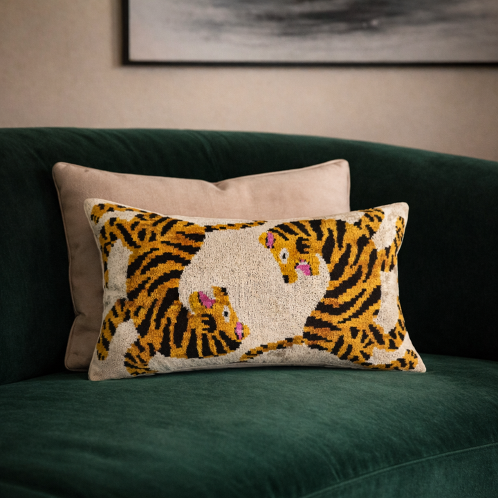 Tiger motif ikat throw pillow cover on green sofa, cream base with yellow and pink accents