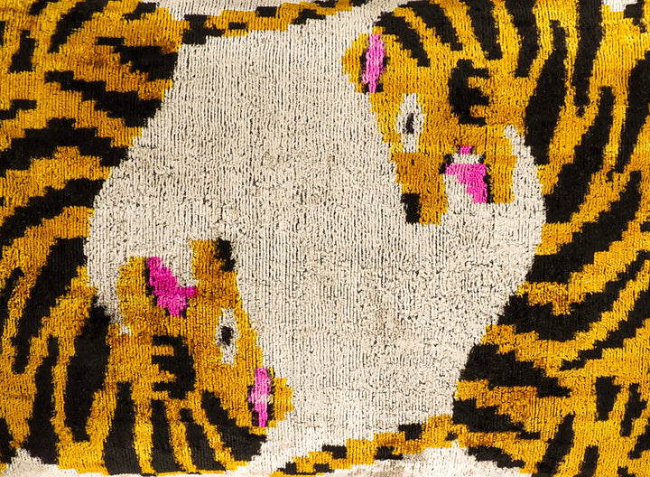 Close-up of embroidered tiger ikat motif on cream throw pillow cover, yellow and pink
