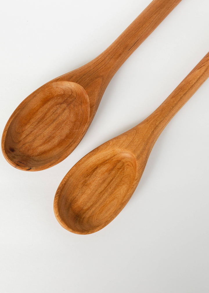Two wooden serving spoons with oval bowls and long handles, warm wood finish