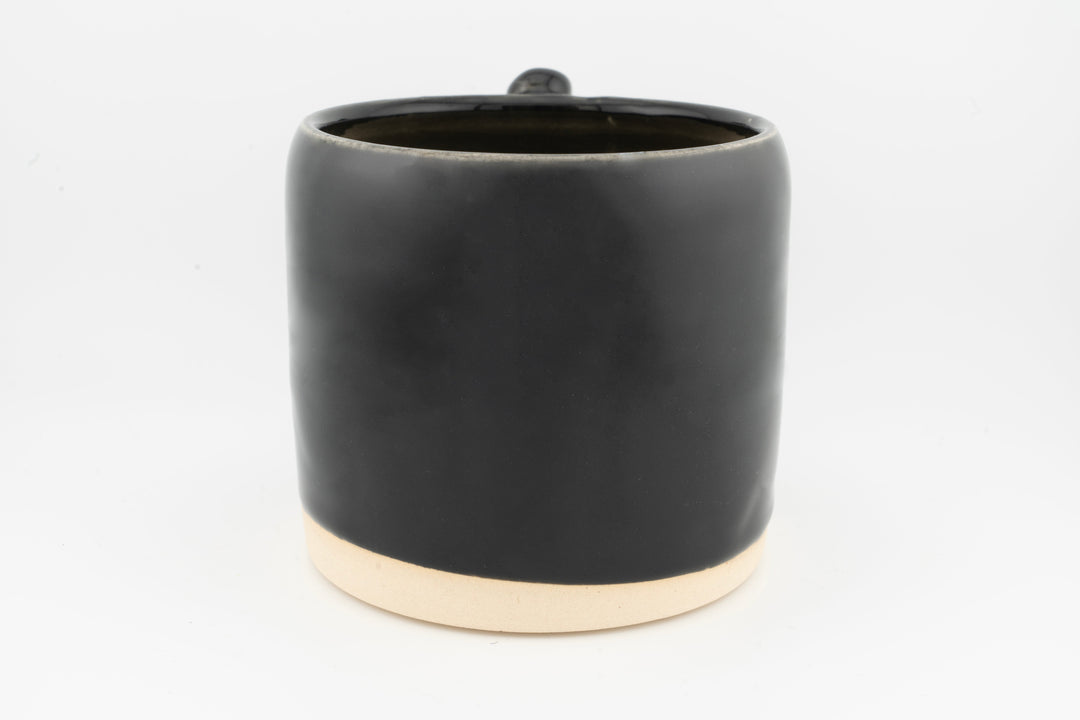 Ceramic mug with glossy black glaze and creamy foot base