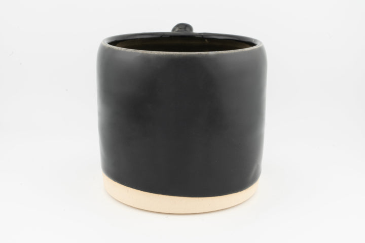 Ceramic mug with glossy black glaze and creamy foot base