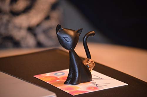 Black cat ring holder figurine on a tabletop, curved tail detail visible