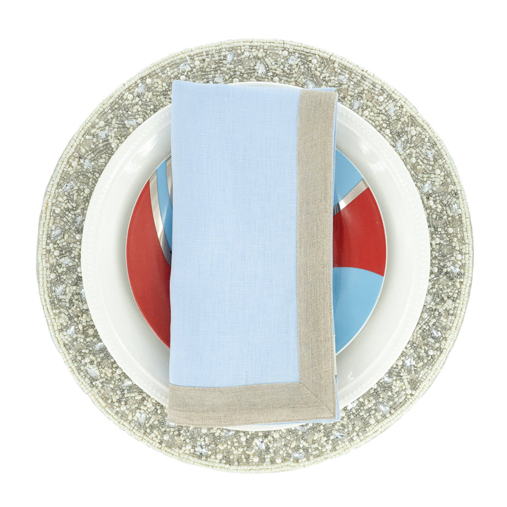 Light blue linen napkin with beige border trim, folded upright